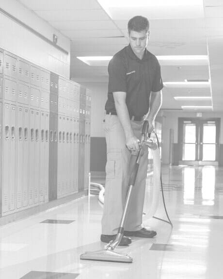 Stanley Steemer technician cleaning VCT floors in school hallway
