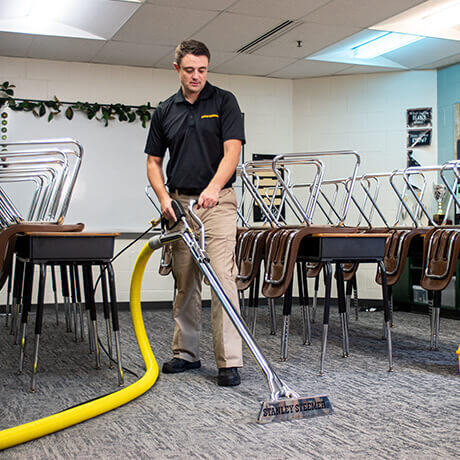 Stanley Steemer technician cleaning carpet in classroom
