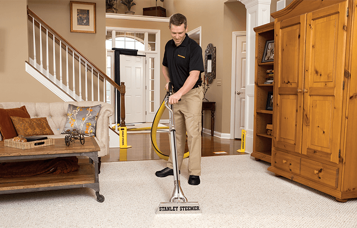 Technician using hot water extraction to clean carpets