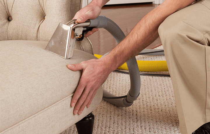Technician using hot water extraction machine to clean upholstery