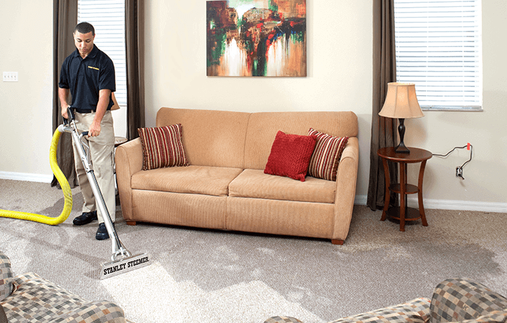 Stanley Steemer technician extracting water from carpet in living room