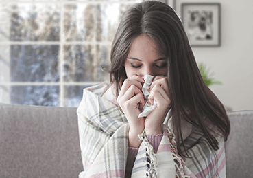 Women blowing her nose into a tissue during the winter