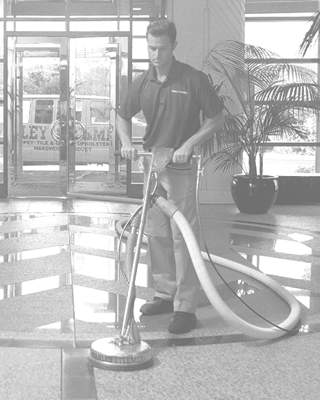 Black and white image of Stanley Steemer technician deep cleaning tile and grout floors in office lobby