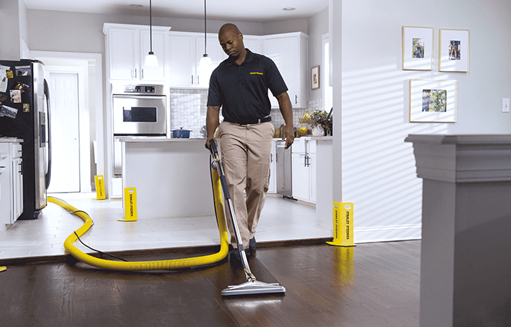 Stanley Steemer technician cleaning hardwood floors in dining room