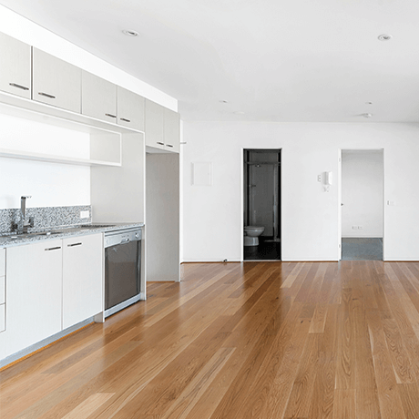 Empty apartment overlooking hardwood floors in kitchen and living space